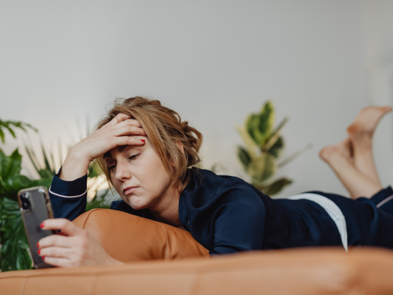 stress breakdown- woman sitting on phone with hand on head.