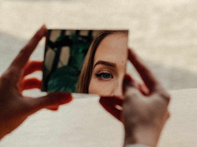 glow up instructions- girl reflection in mirror with beach in background.